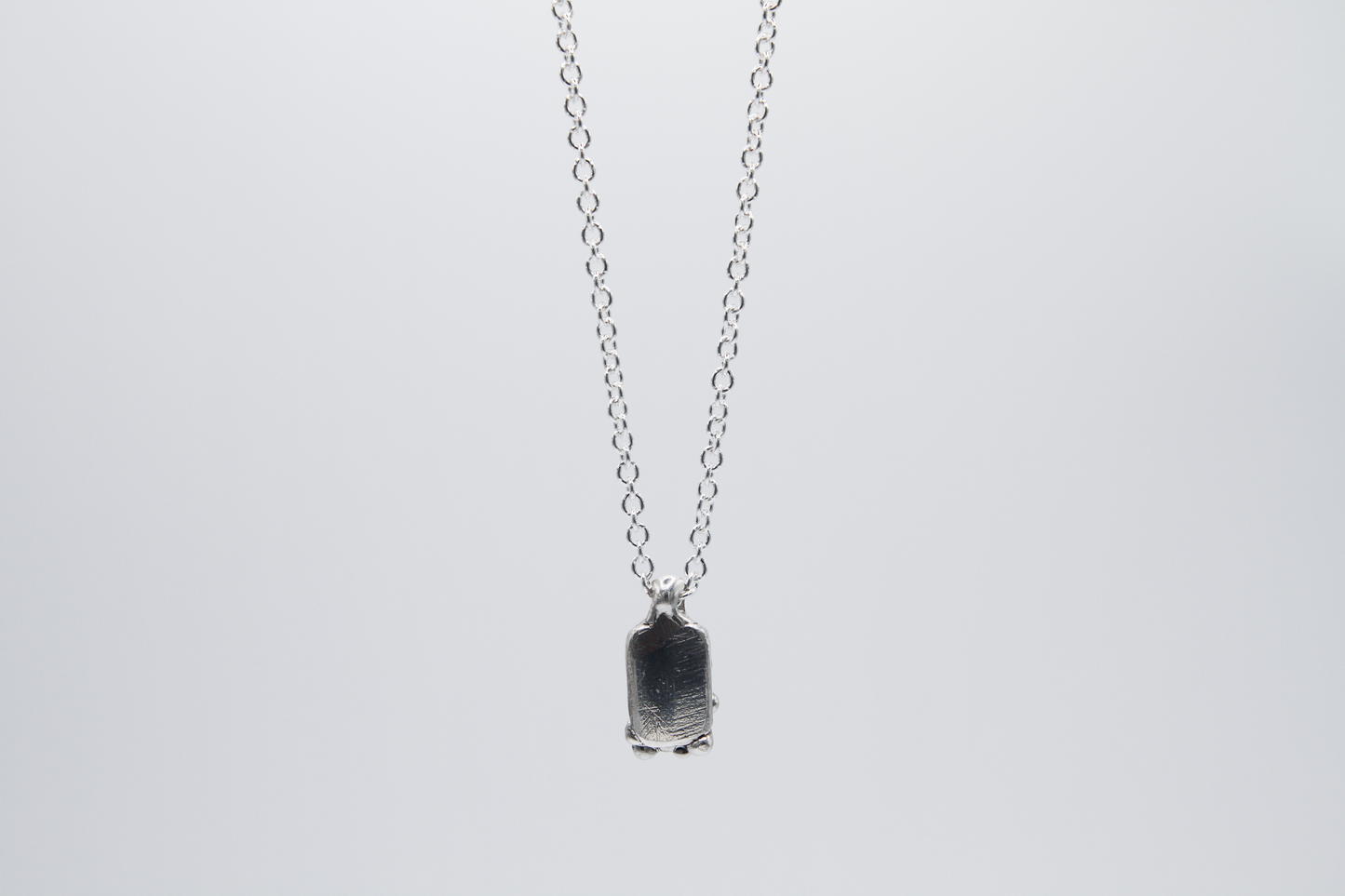 The Treacle Pendant Necklace. 925 Solid Sterling Silver Pendant Necklace hand made in the United Kingdom. This necklace displays a tag style pendant with a melted and dripping texture formed by solid sterling silver. This pendant sits on an 18 inch cable chain. For all genders.