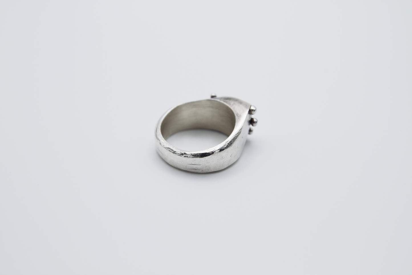 The Dew Drop Signet. 925 Solid Sterling Silver Ring hand made in the United Kingdom. This ring fashions a signet styler shape that slants to the left in a pointed oval shape. There are 3 silver balls on each side of the ring face.