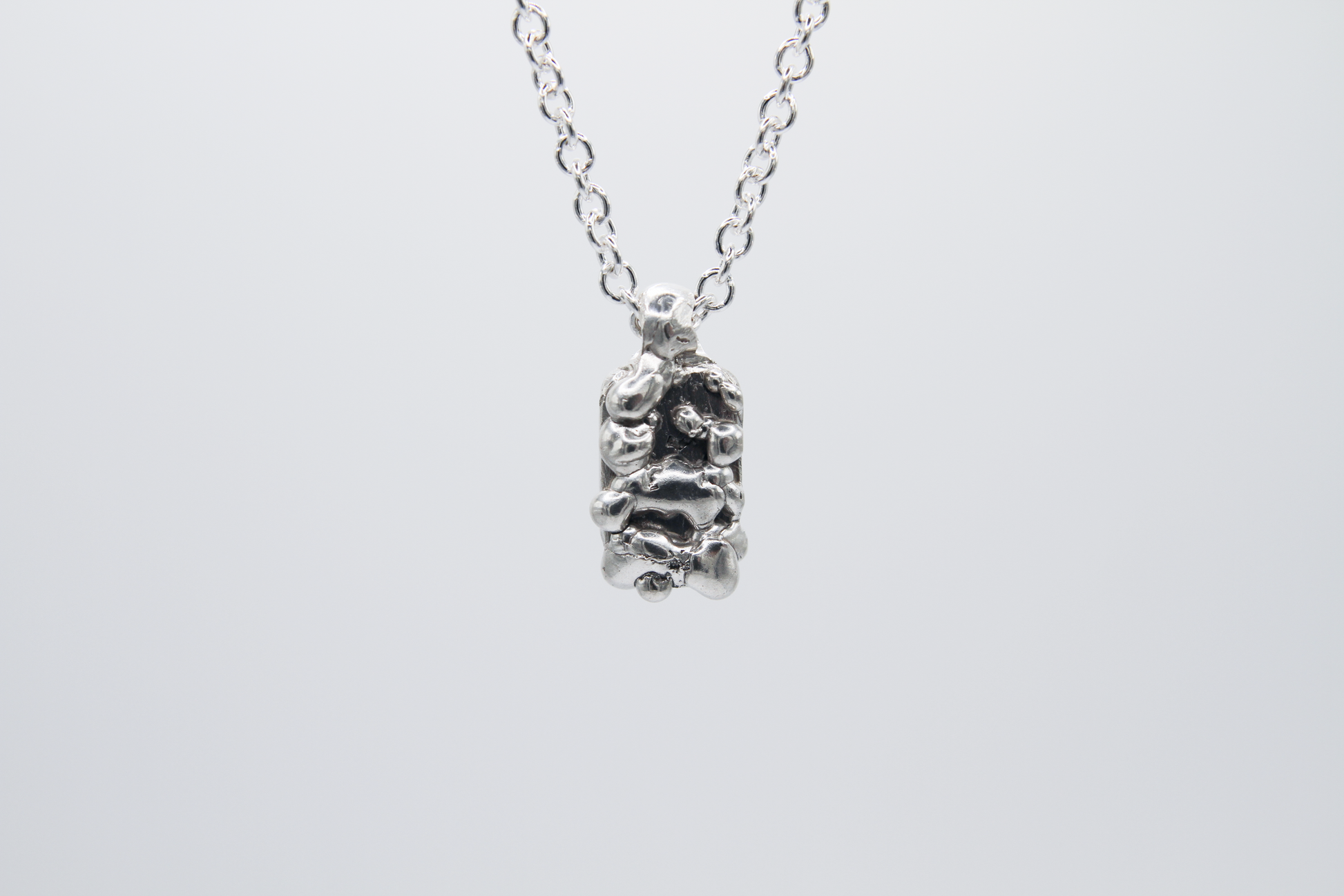 The Treacle Pendant Necklace. 925 Solid Sterling Silver Pendant Necklace hand made in the United Kingdom. This necklace displays a tag style pendant with a melted and dripping texture formed by solid sterling silver. This pendant sits on an 18 inch cable chain. For all genders.