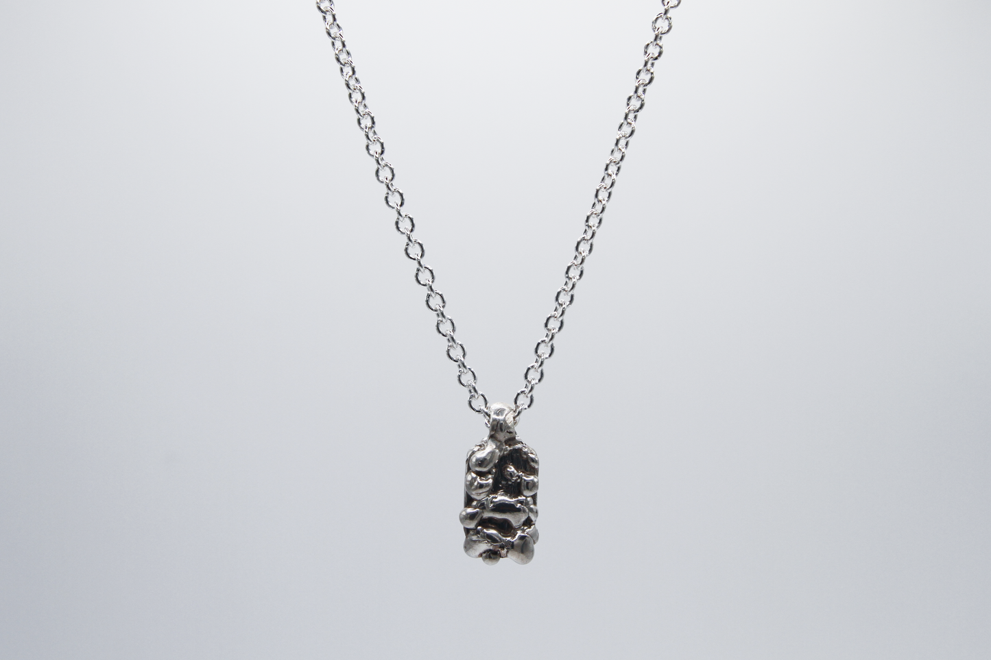 The Treacle Pendant Necklace. 925 Solid Sterling Silver Pendant Necklace hand made in the United Kingdom. This necklace displays a tag style pendant with a melted and dripping texture formed by solid sterling silver. This pendant sits on an 18 inch cable chain. For all genders.