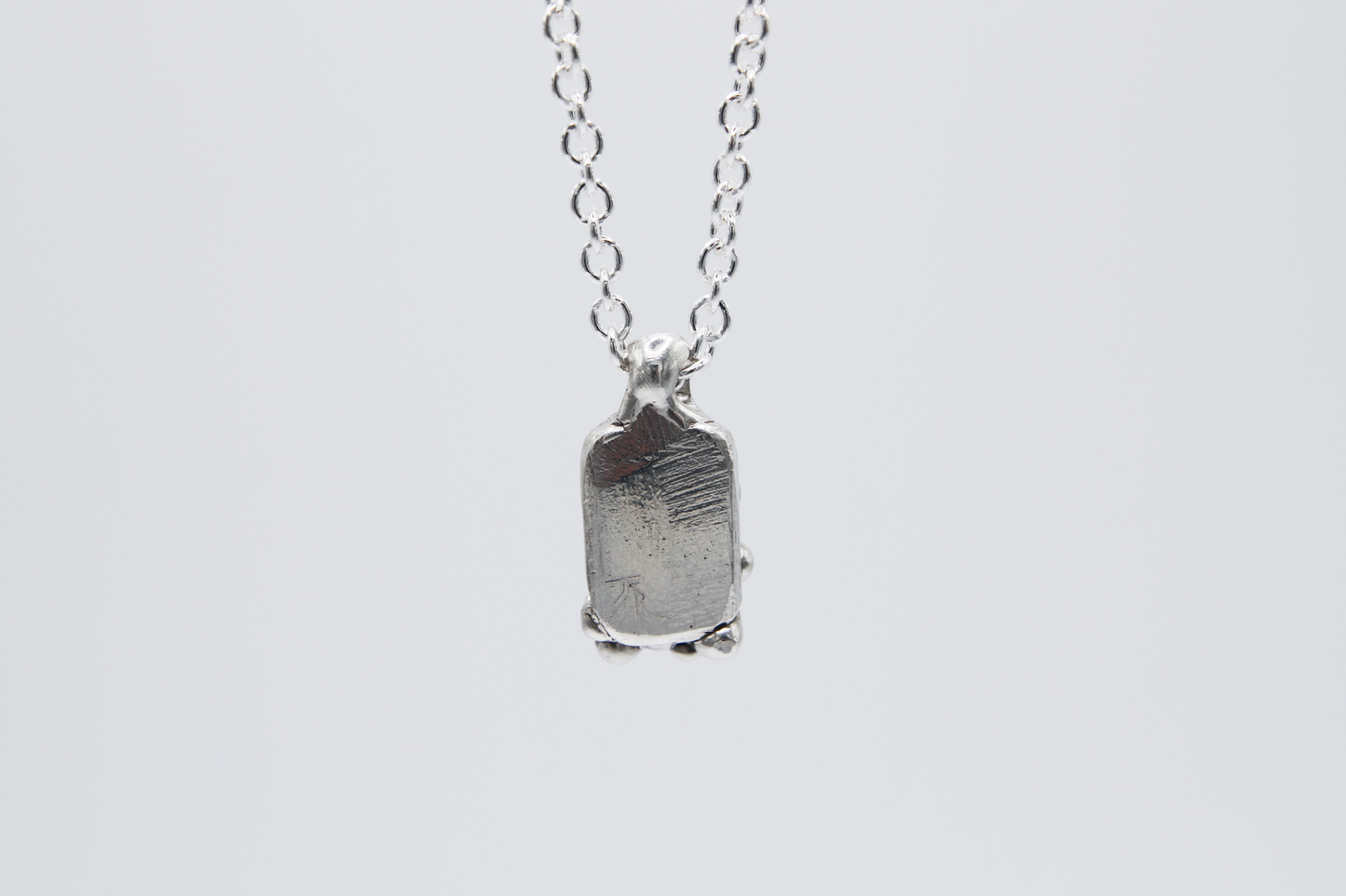 The Treacle Pendant Necklace. 925 Solid Sterling Silver Pendant Necklace hand made in the United Kingdom. This necklace displays a tag style pendant with a melted and dripping texture formed by solid sterling silver. This pendant sits on an 18 inch cable chain. For all genders.