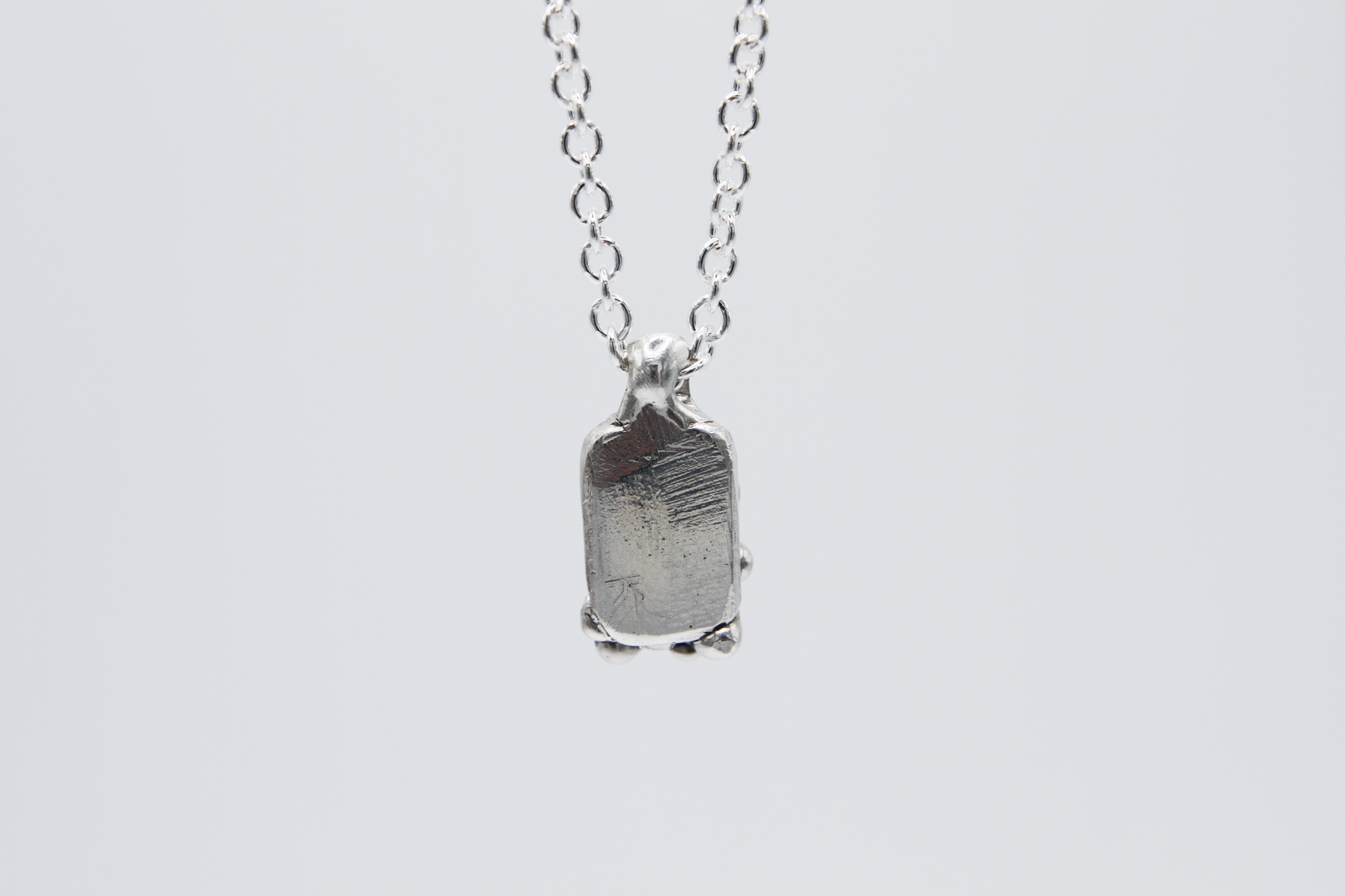 The Treacle Pendant Necklace. 925 Solid Sterling Silver Pendant Necklace hand made in the United Kingdom. This necklace displays a tag style pendant with a melted and dripping texture formed by solid sterling silver. This pendant sits on an 18 inch cable chain. For all genders.