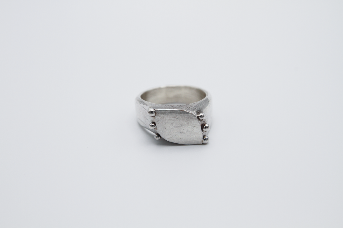 The Dew Drop Signet. 925 Solid Sterling Silver Ring hand made in the United Kingdom. This ring fashions a signet styler shape that slants to the left in a pointed oval shape. There are 3 silver balls on each side of the ring face.