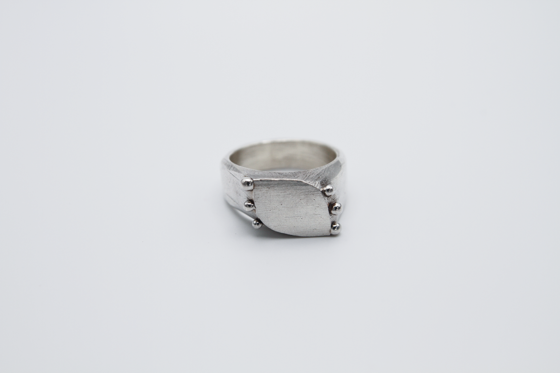 The Dew Drop Signet. 925 Solid Sterling Silver Ring hand made in the United Kingdom. This ring fashions a signet styler shape that slants to the left in a pointed oval shape. There are 3 silver balls on each side of the ring face.