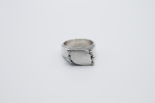 The Dew Drop Signet. 925 Solid Sterling Silver Ring hand made in the United Kingdom. This ring fashions a signet styler shape that slants to the left in a pointed oval shape. There are 3 silver balls on each side of the ring face.