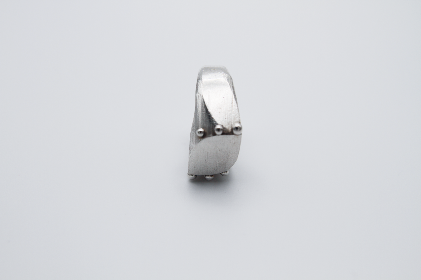 The Dew Drop Signet. 925 Solid Sterling Silver Ring hand made in the United Kingdom. This ring fashions a signet styler shape that slants to the left in a pointed oval shape. There are 3 silver balls on each side of the ring face.