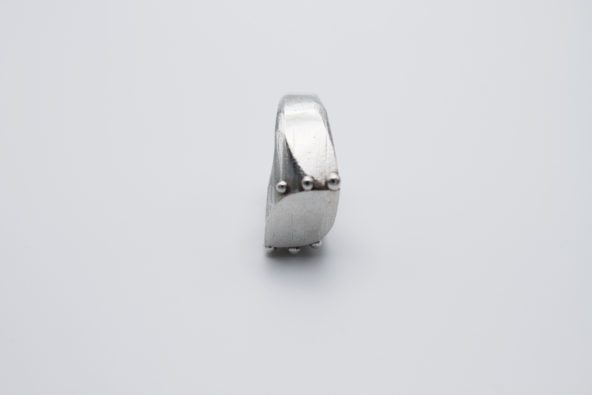 The Dew Drop Signet. 925 Solid Sterling Silver Ring hand made in the United Kingdom. This ring fashions a signet styler shape that slants to the left in a pointed oval shape. There are 3 silver balls on each side of the ring face.